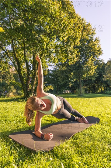 Young woman in sportswear doing side plank