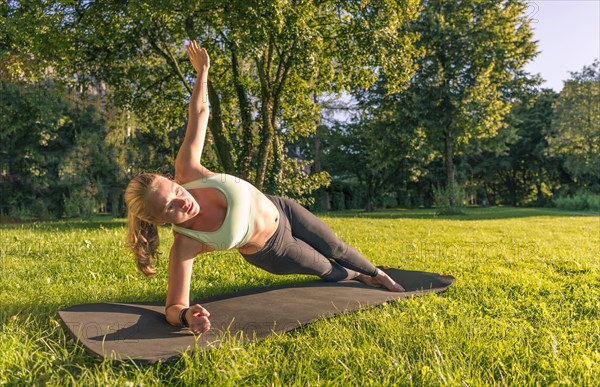 Young woman in sportswear doing side plank