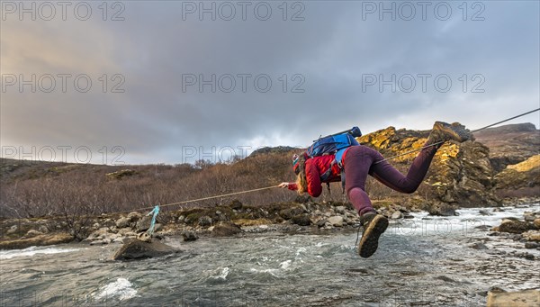 Young woman crossing river with rope