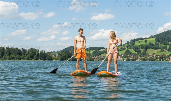 Young man and woman standing on paddle boards
