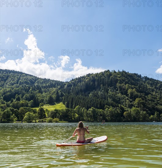 Young woman sitting on a Standup-Paddle Board or SUP