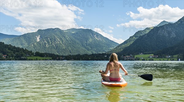 Young woman sitting on a Standup-Paddle Board or SUP