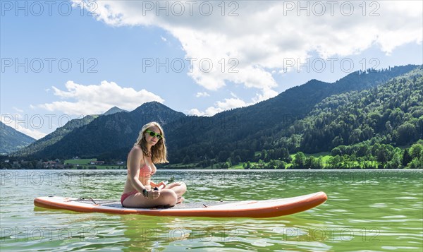 Young woman sitting on a Standup-Paddle Board or SUP