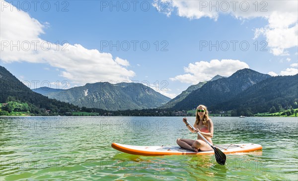 Young woman sitting on a Standup-Paddle Board or SUP