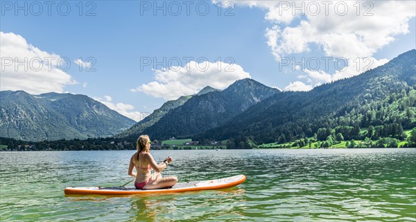 Young woman sitting on a Standup-Paddle Board or SUP