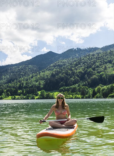 Young woman sitting on a Standup-Paddle Board or SUP