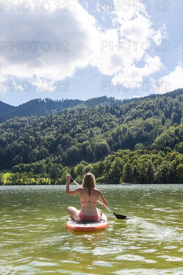 Young woman sitting on a Standup-Paddle Board or SUP