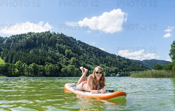 Young woman lying on a Standup-Paddle Board or SUP