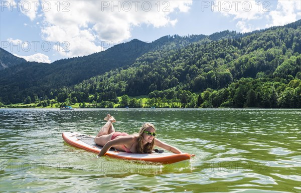 Young woman lying on a Standup-Paddle Board or SUP