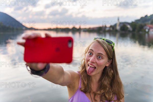 Young woman taking selfie with outstretched tongue