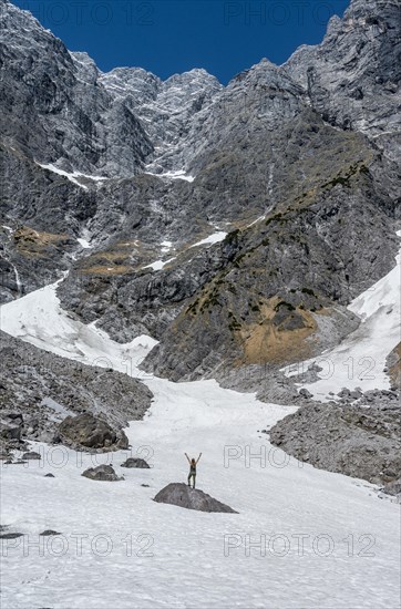 Hiker standing on rock with arms outstretched