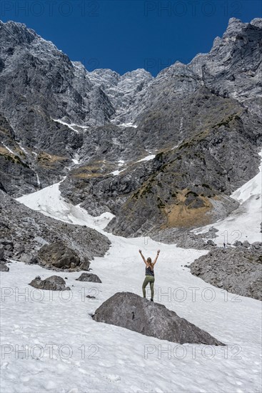 Hiker standing on rock with arms outstretched