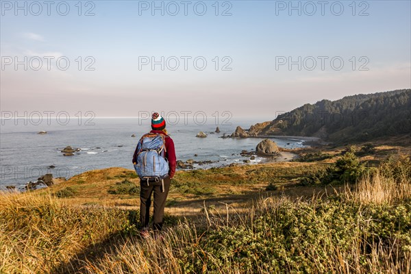 Young woman on a hiking trail along the rugged coast with many rocks