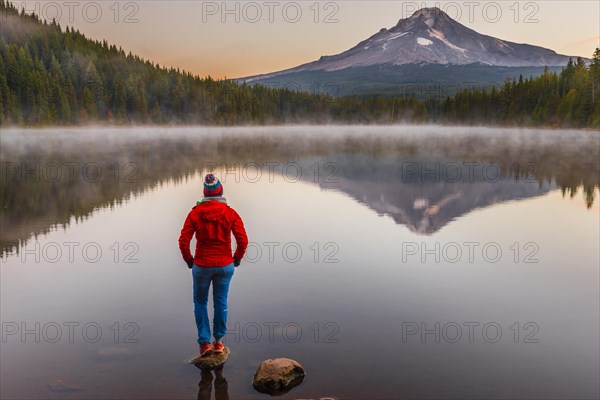 Young woman looking at view of volcano Mt. Hood with reflection in lake Trillium Lake