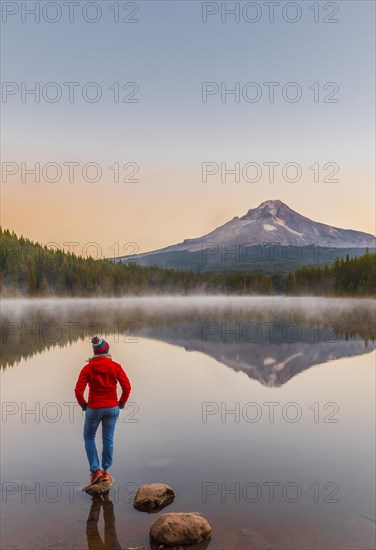 Young woman looking at view of volcano Mt. Hood with reflection in lake Trillium Lake