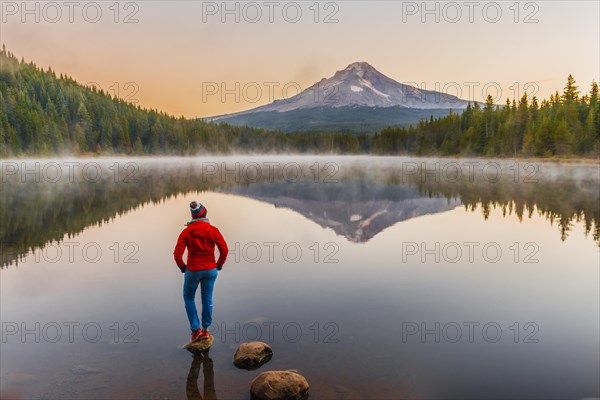 Young woman looking at view of volcano Mt. Hood with reflection in lake Trillium Lake