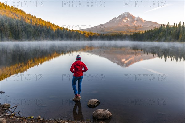 Young woman looking at view of volcano Mt. Hood with reflection in lake Trillium Lake