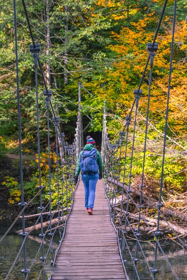 Young woman walking on a suspension bridge across a river