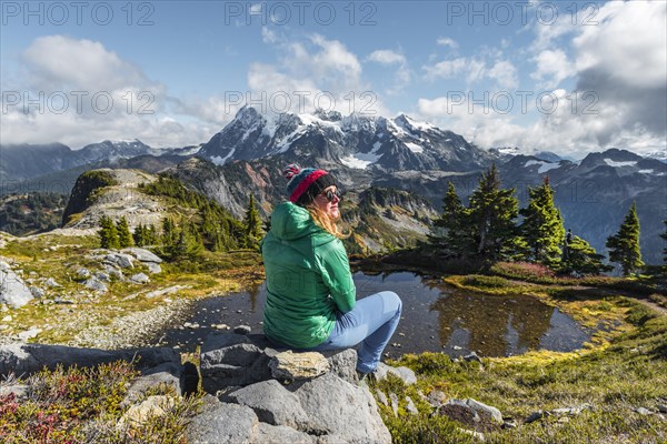 Female hiker resting on a rock at a small mountain lake