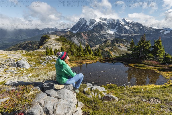 Female hiker resting on a rock at a small mountain lake