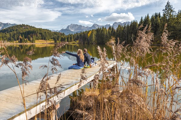 Two young women sitting at a jetty having a snack