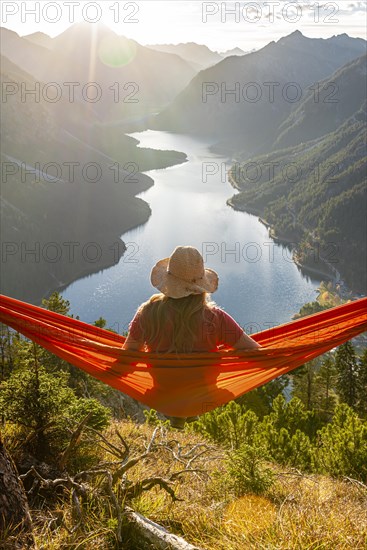 Woman with a sun hat sitting in an orange hammock