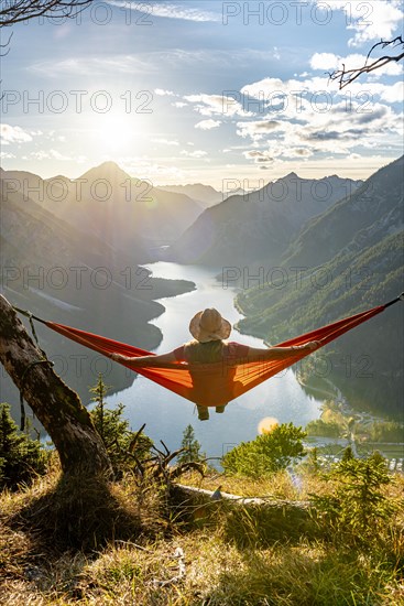 Woman with a sun hat sitting in an orange hammock