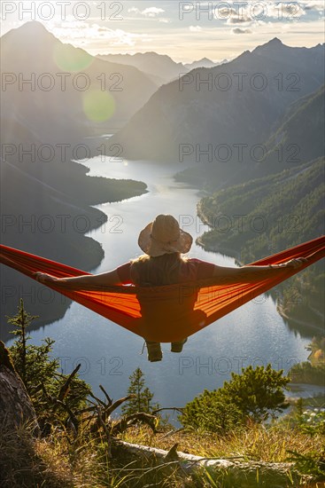 Woman with a sun hat sitting in an orange hammock