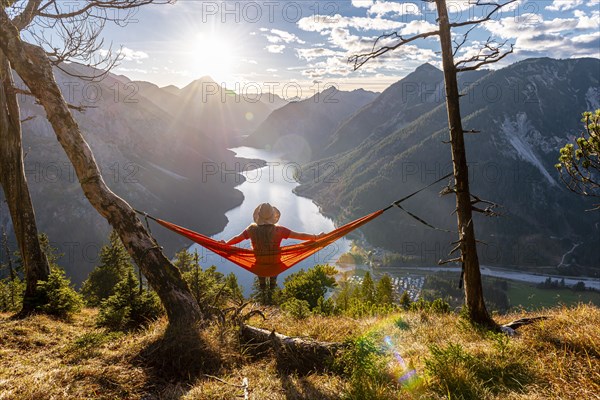 Woman with a sun hat sitting in an orange hammock