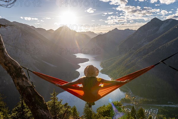 Woman with a sun hat sitting in an orange hammock