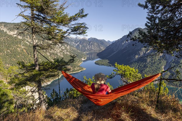 Woman with a sun hat sitting in an orange hammock