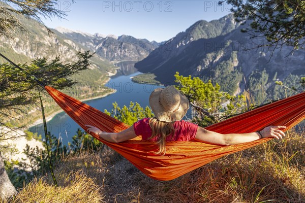 Woman with a sun hat sitting in an orange hammock