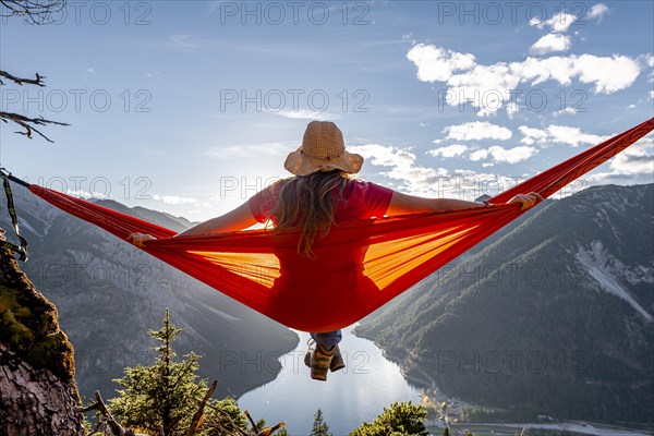 Woman with a sun hat sitting in an orange hammock