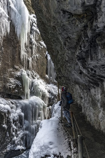 Young woman in the icy Partnachklamm with icicles and snow in winter