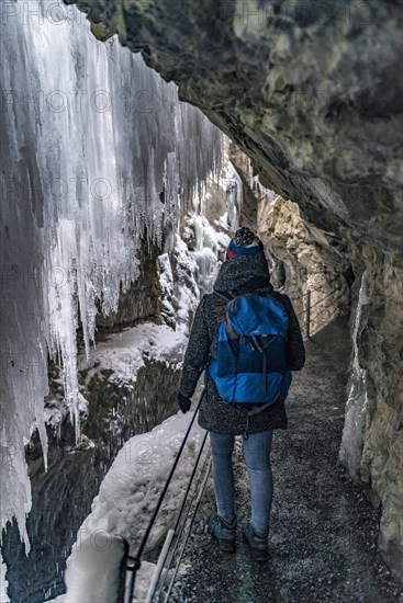 Young woman in the icy Partnachklamm with icicles and snow in winter