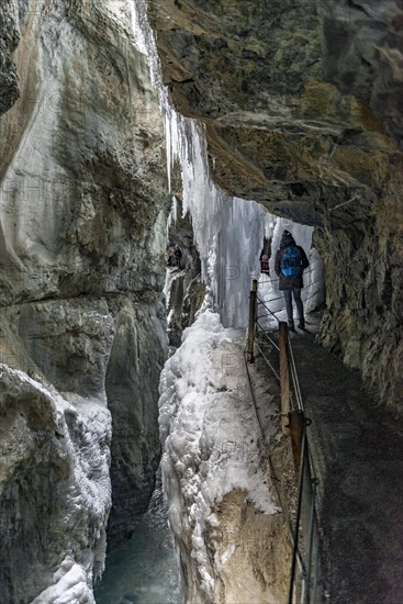 Young woman in the icy Partnachklamm with icicles and snow in winter