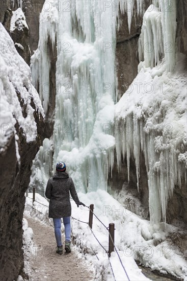 Young woman in the icy Partnachklamm with icicles and snow in winter