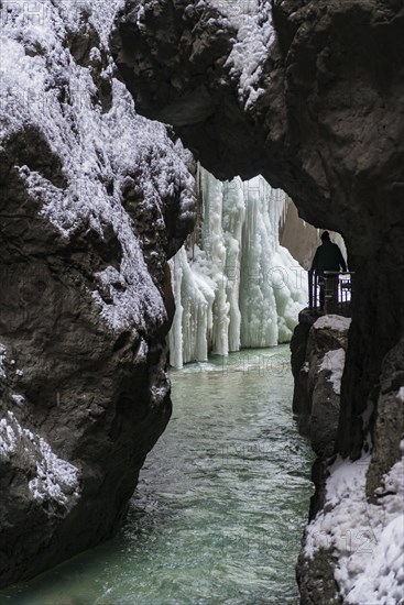 Young woman in the icy Partnachklamm with icicles and snow in winter