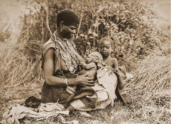 African woman with two small child seats in the grass