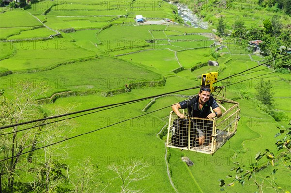 Man in a cargo seat above Hapao rice terraces