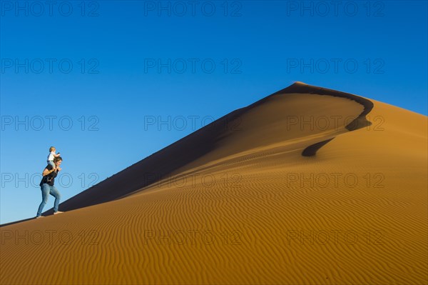 Woman with her baby walking up the giant sanddune Dune 45