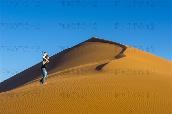 Woman with her baby walking up the giant sanddune Dune 45
