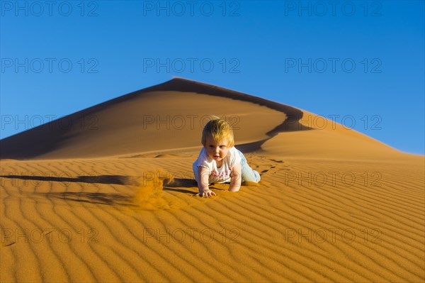 Baby crawling down in the sand