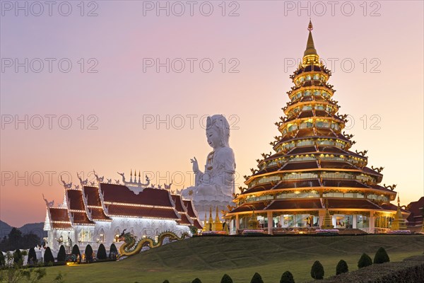 Nine-storey Chinese pagoda and chapel in front of huge Guan Yin statue at sunset