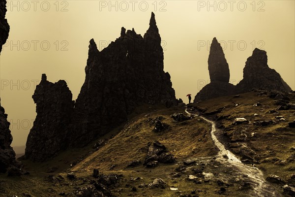 Rock Old Man of Storr with tourist with red umbrella