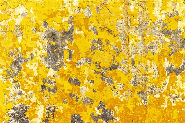 Crumbling plaster on yellow house wall