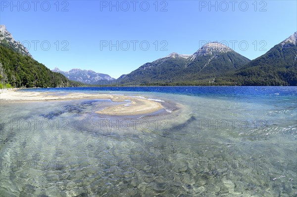 Lake with crystal clear water in front of mountain landscape