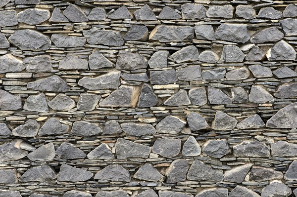 Wall of layered ground-down basalt stones and slates