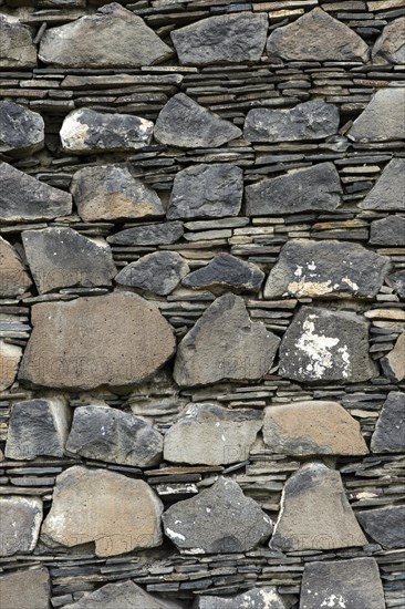 Wall of layered ground-down basalt stones and slates