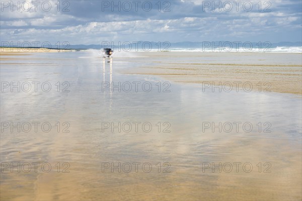 Black Hyundai Santa Fe 4x4 off-road vehicle drives on the sandy beach of Ninety Mile Beach in the water